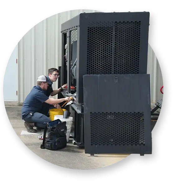 Two Devall Diesel technicians looking a diesel generator outside of a warehouse